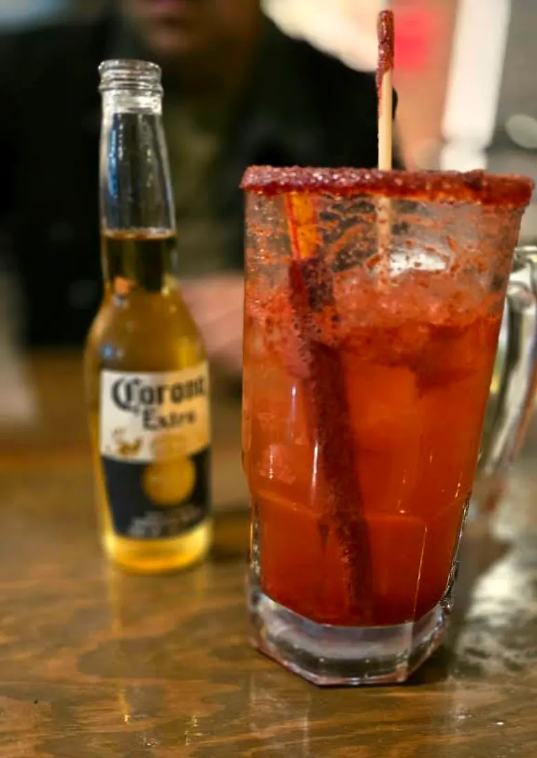 Tarro michelado escarchado con chile junto a una Corona