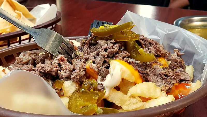 Papas a la francesa con top sirloin picado, queso amarillo, mayonesa y rajas de jalapeño en canasta